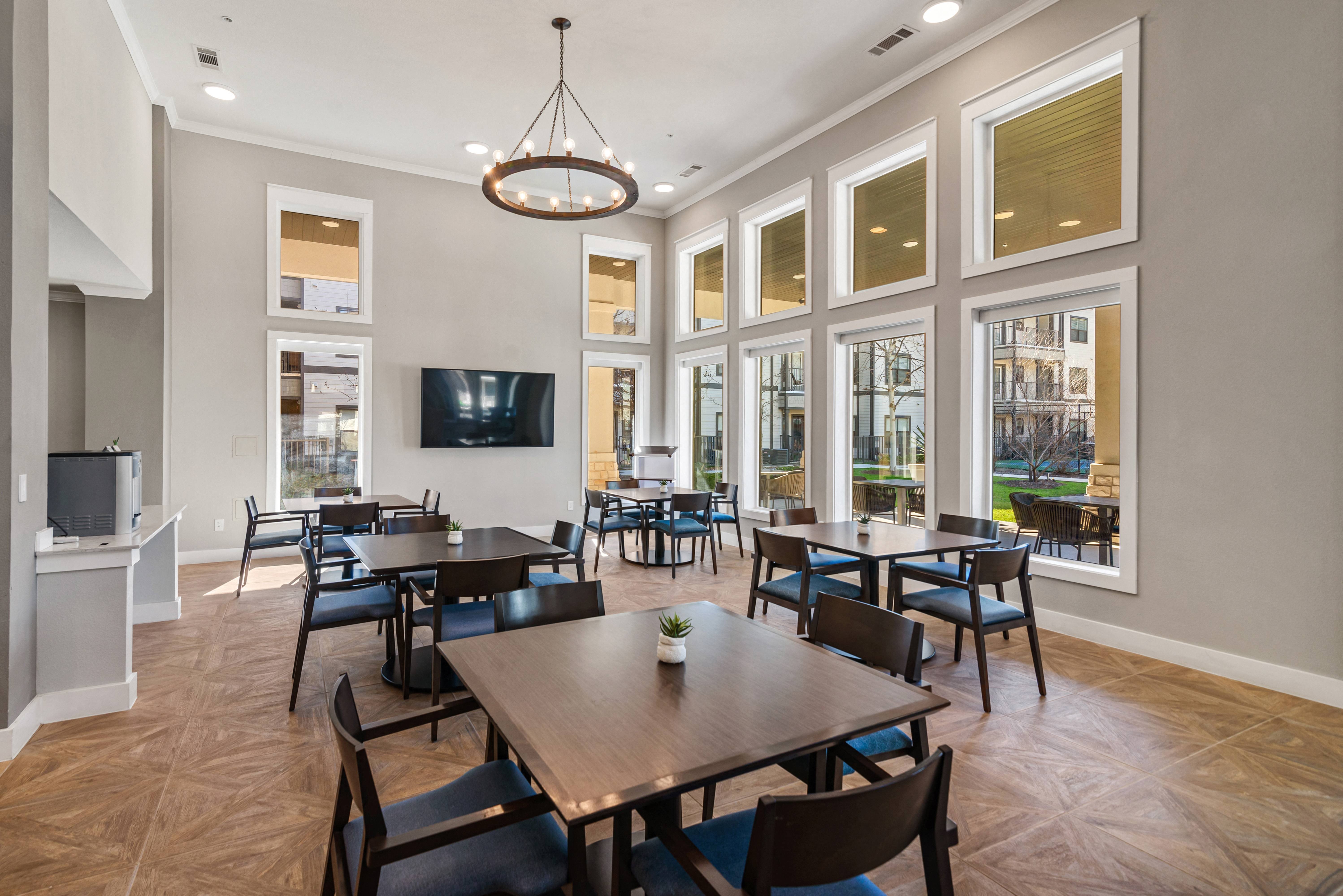 a communal clubhouse dining room with tables and chairs at a senior apartment community